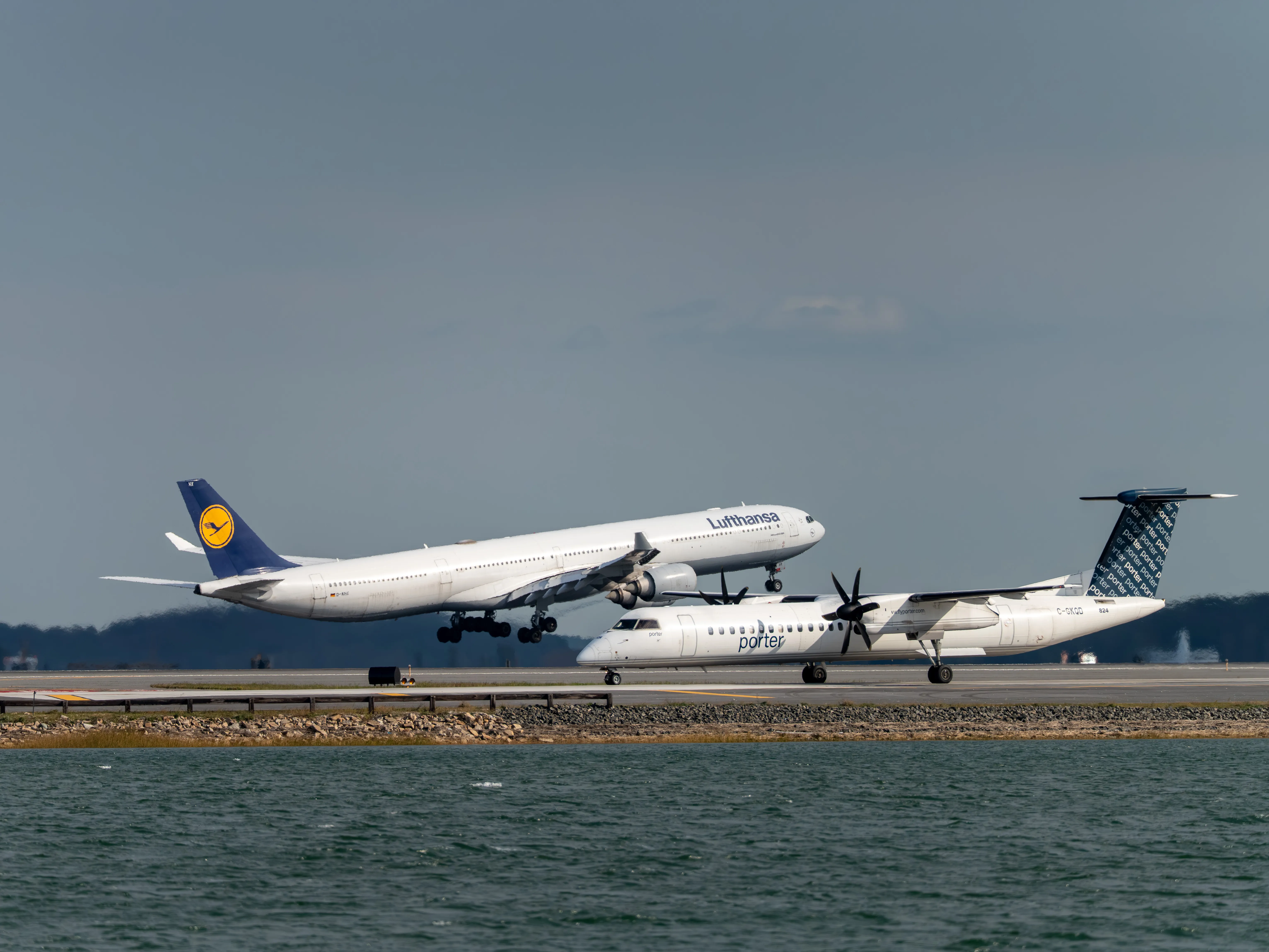 Lufthansa Airbus A340-600 (registration number D-AIHX) approaching and Porter Airlines De Havilland Canada Dash 8-400 (registration number C-GKQD) taxiing