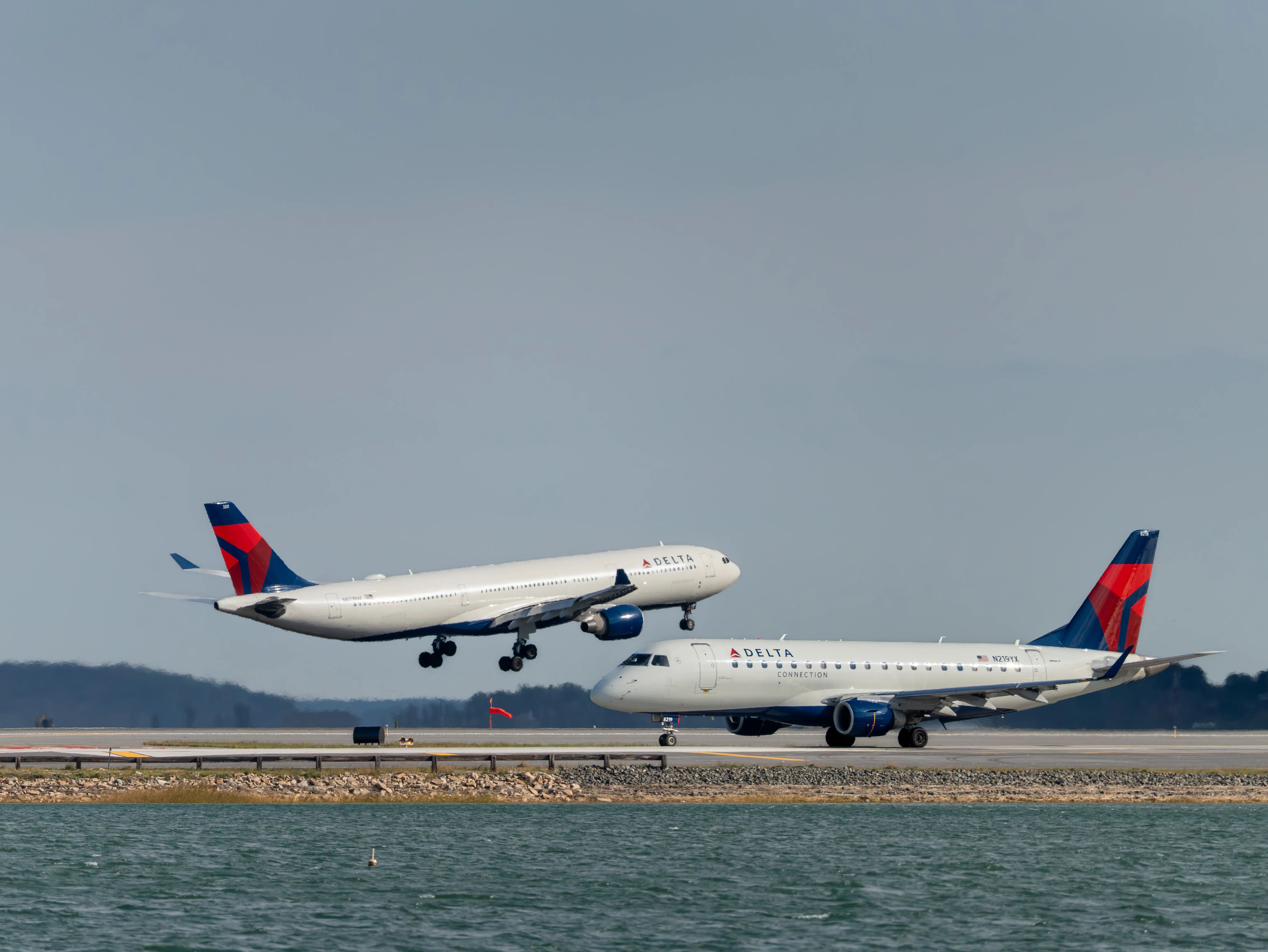Two Delta Aeroplanes: Delta Air Lines Airbus A330-323 (N801NW) Making Final Approach and Delta Air Lines Embraer E175LR (N219YX) Taxiing