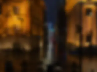 Cars on the Jiujiang Road with old amber buildings and high blue buildings in the background (night sight)