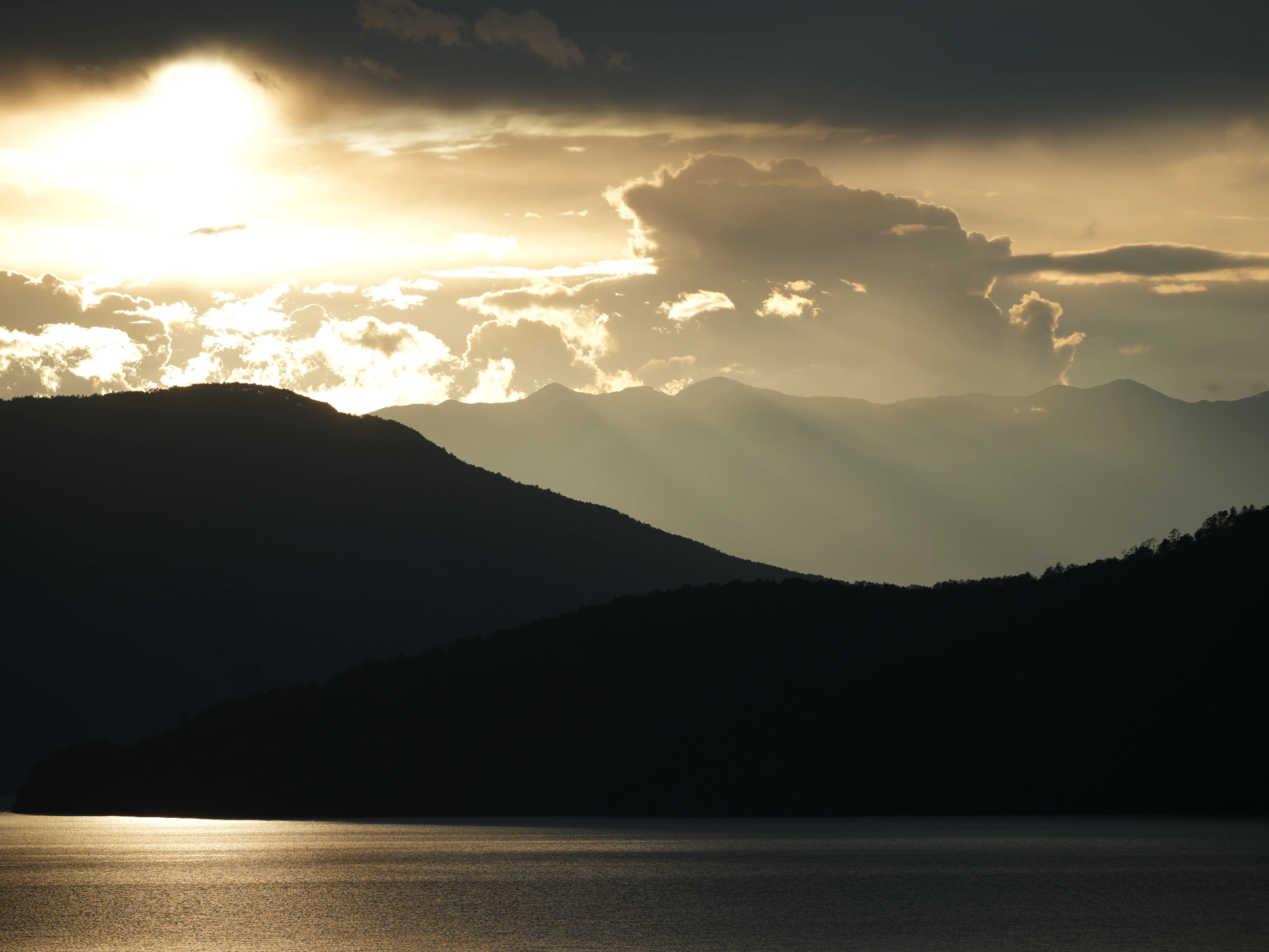 Sunset beams of Lugu Lake in golden colour and mountains